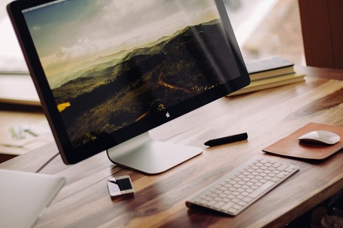 computer-with-landscape-on-screen-and-mobile-phone-on-wooden-table.jpg