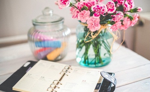 personal-organizer-and-bunch-of-pink-flowers-in-vase-on-desk.jpg